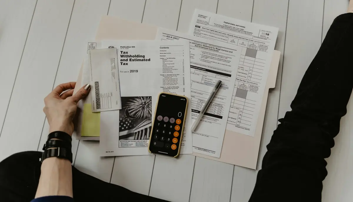 Hands working through paperwork with a calculator on a desk